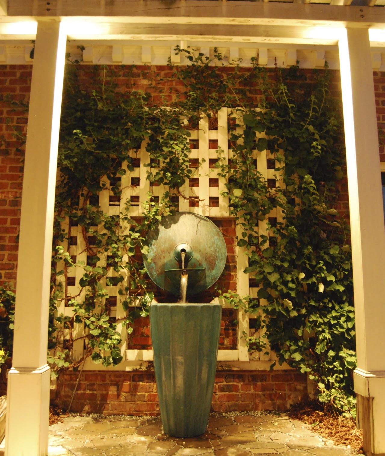 Illuminated wall fountain with lattice and greenery built by Toms Creek