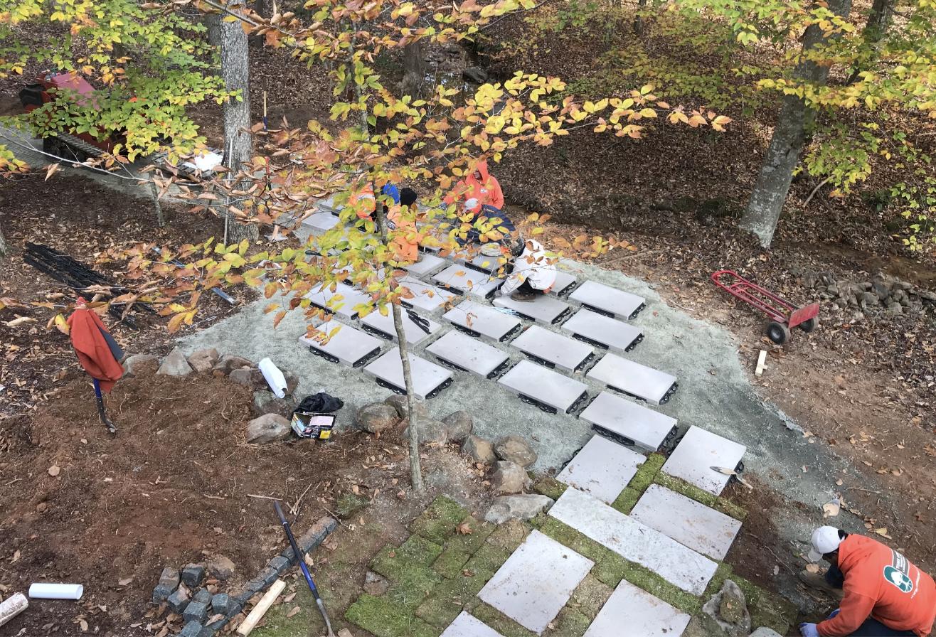 Large paver slabs being set into a wooded hillside walkway