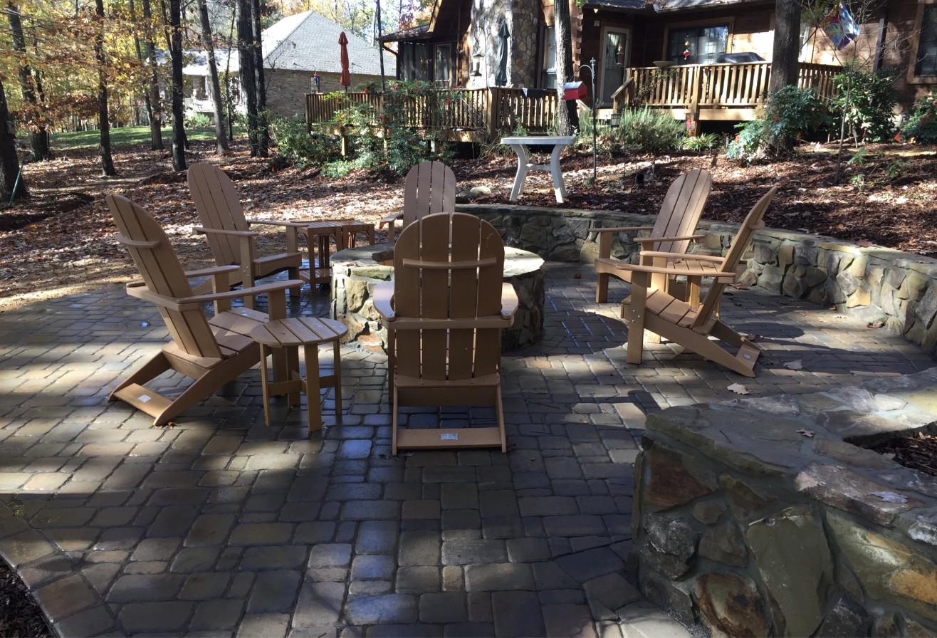 Circular paver patio with stone fire pit and Adirondack chairs